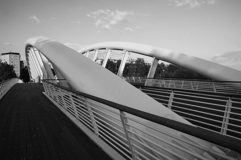 Railing by bridge against sky