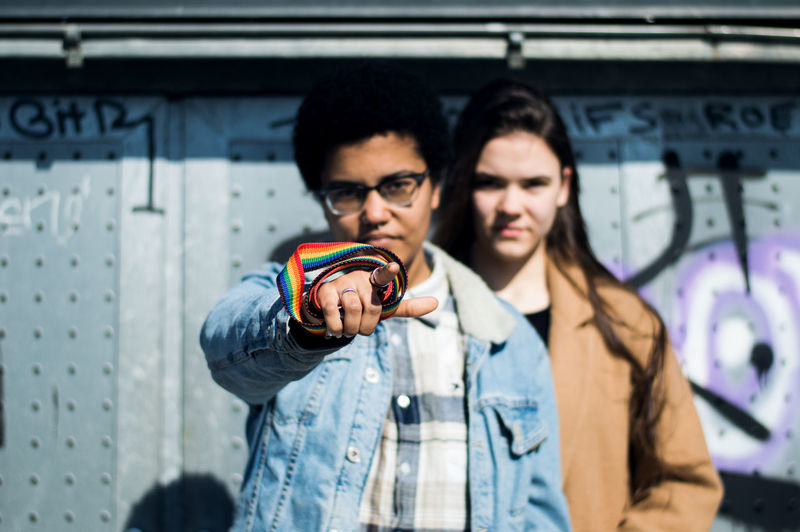 Casual Clothing Communication Day Glasses Graffiti Hairstyle Homosexual Love Leisure Activity Lifestyles Outdoors People Real People Standing Technology Teenager Togetherness Two People Waist Up Young Adult Young Women This Is Queer Focus On The Story