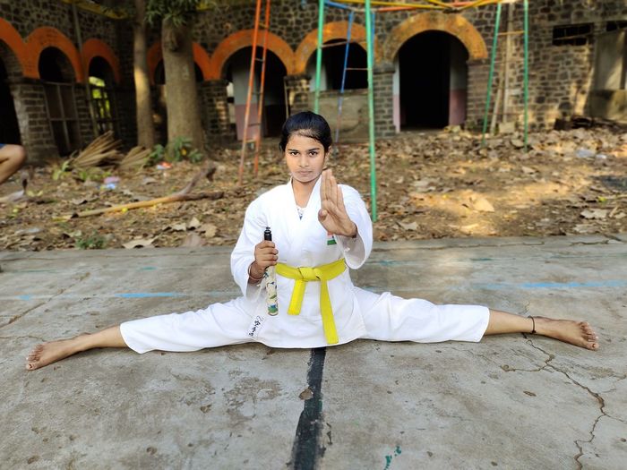 Full length portrait of young woman practicing martial art outdoors