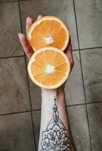 High angle view of hand holding orange on floor