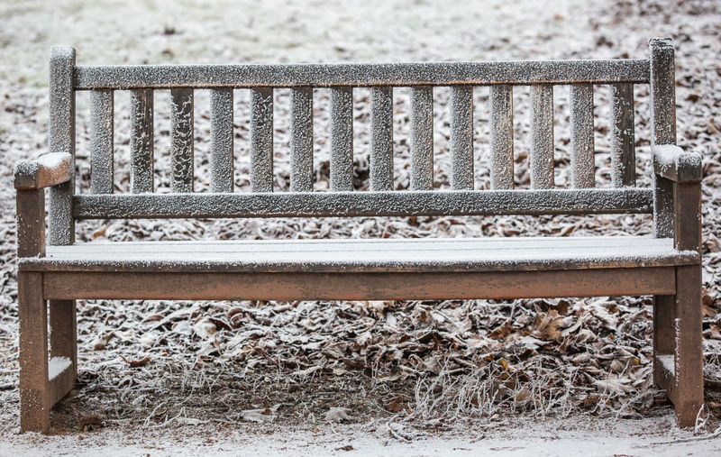 Close-up of empty bench in park during winter