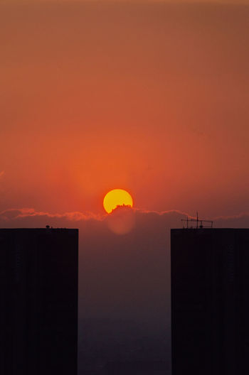 Silhouette buildings against orange sky