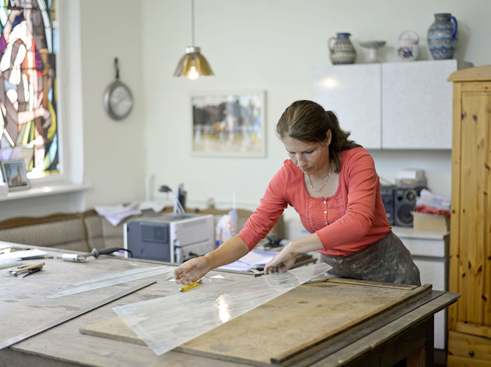 Woman working on glass pane in glazier's workshop