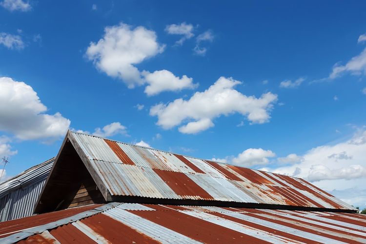 Low angle view of building roof against cloudy sky