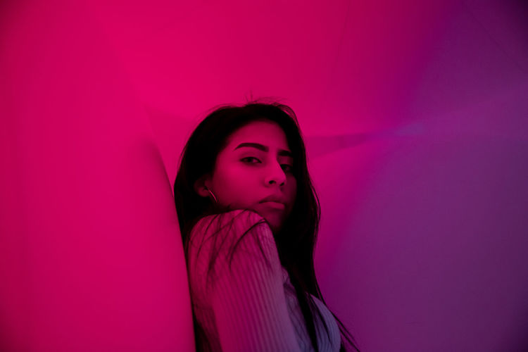 Portrait of woman standing against pink wall