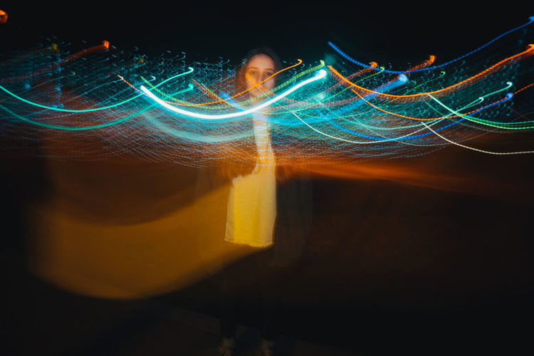 Digital composite image of woman and light painting at night