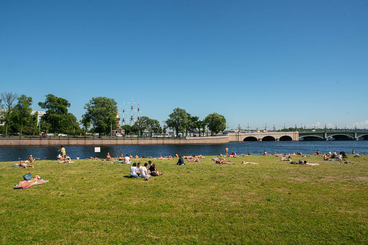People on field by river against clear sky