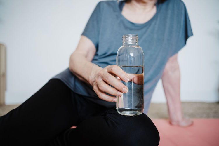 Midsection of woman holding glass bottle