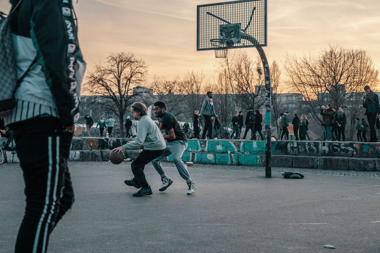People playing basketball on city against sky