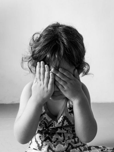 Portrait of little girl covering face with hand