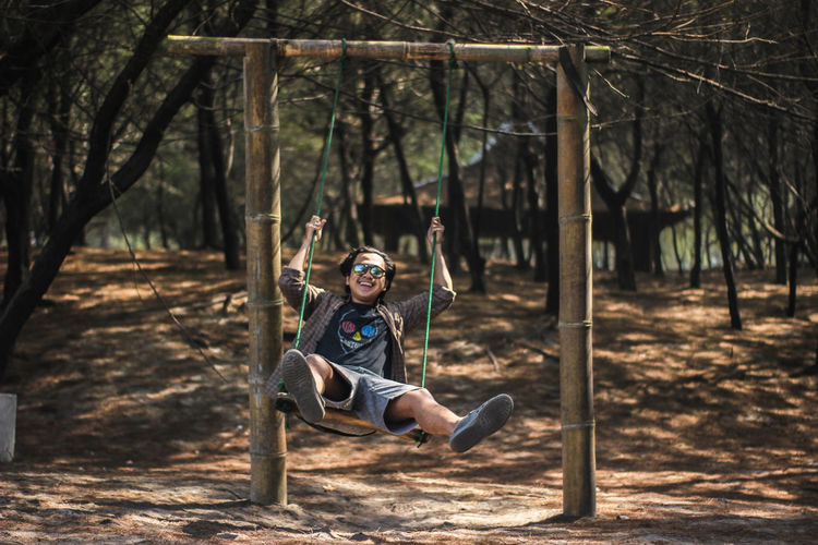 Portrait of young man sitting playing on swing