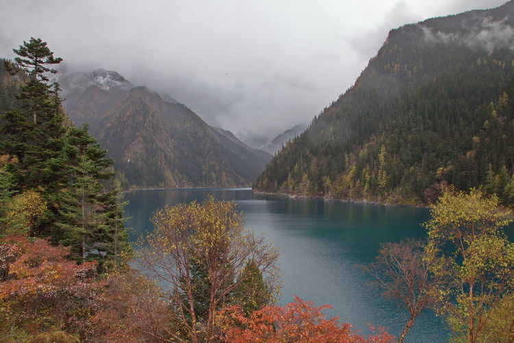 Scenic view of lake and foggy autumn mountains against sky with blue lake
