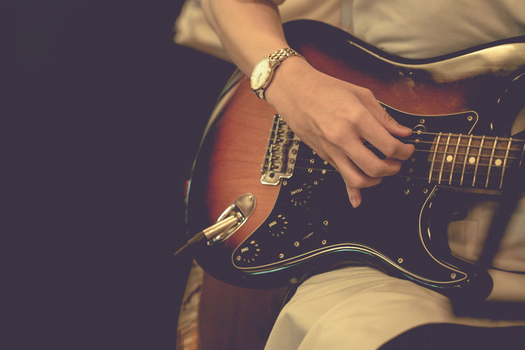 A musician playing guitar at night with warm-toned noise.