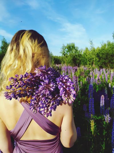 Midsection of woman with purple flowering plants