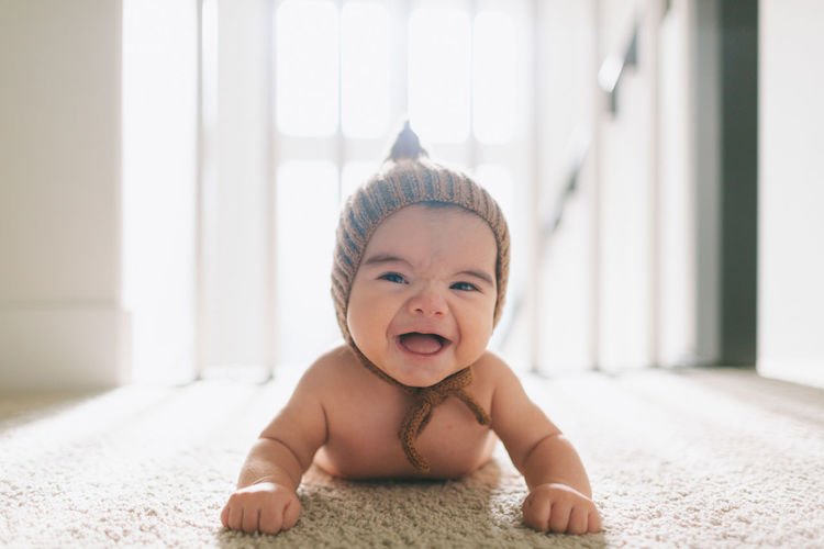 Portrait of cute baby boy on carpet at home
