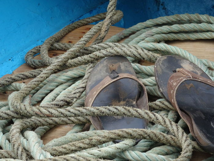 High angle view of old slippers by rope on boat deck