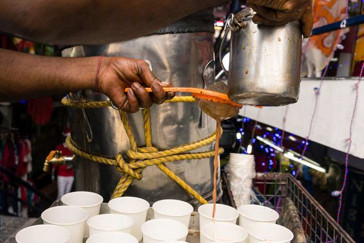 Cropped hands of man serving tea in cups