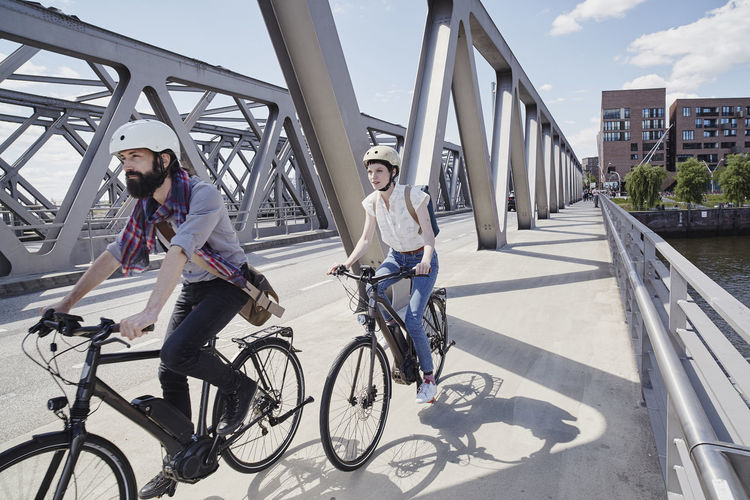 Germany, hamburg, couple riding electric bicycles on a bridge