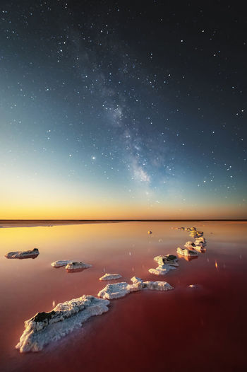Night landscape of a pink salt lake against the backdrop of the starry sky and the milky way.