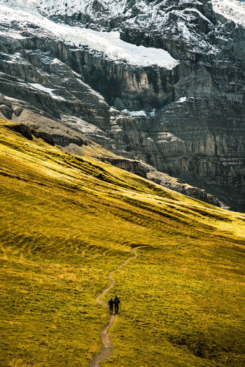 Full length of couple walking on field against mountain range