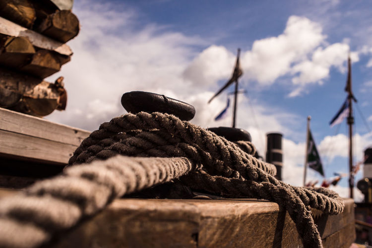 Close-up of a mooring line of a sailboat secured around bollard/mooring post against sky