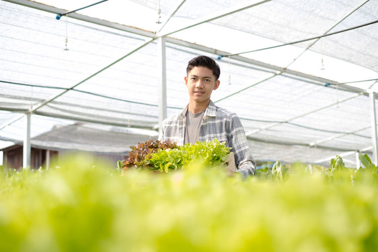 Portrait of man standing in greenhouse