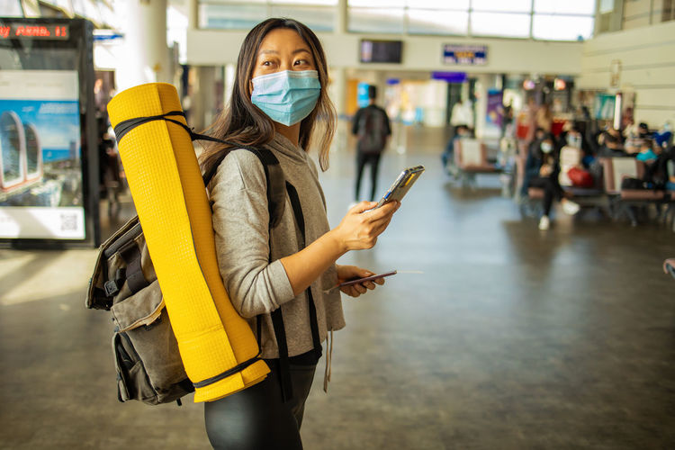 Chinese passenger with mask and smartphone in airport