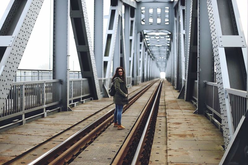 Portrait of young woman standing on railway bridge