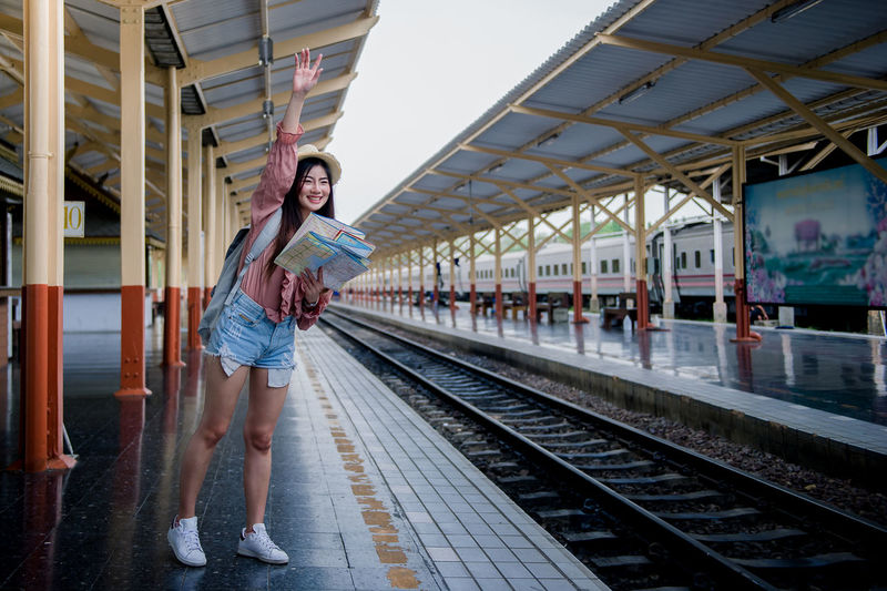 Portrait of young woman standing on railroad station platform