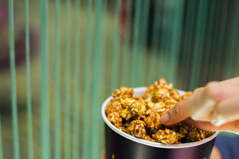 Cropped image of hand holding caramel popcorn at theatre
