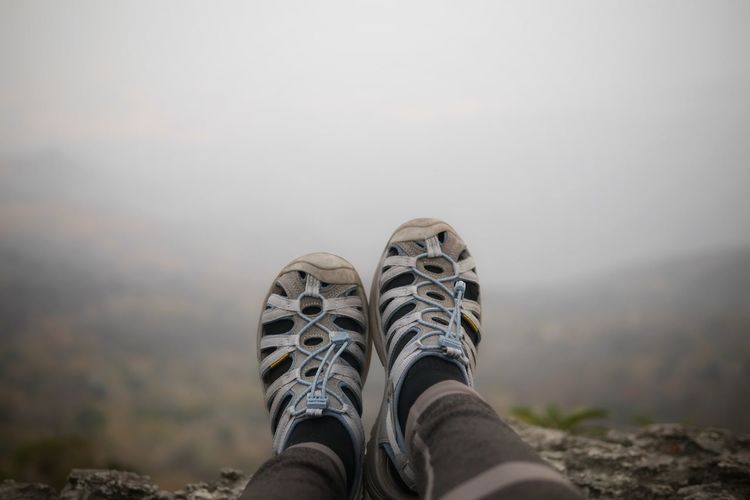 Low section of person wearing shoes against sky