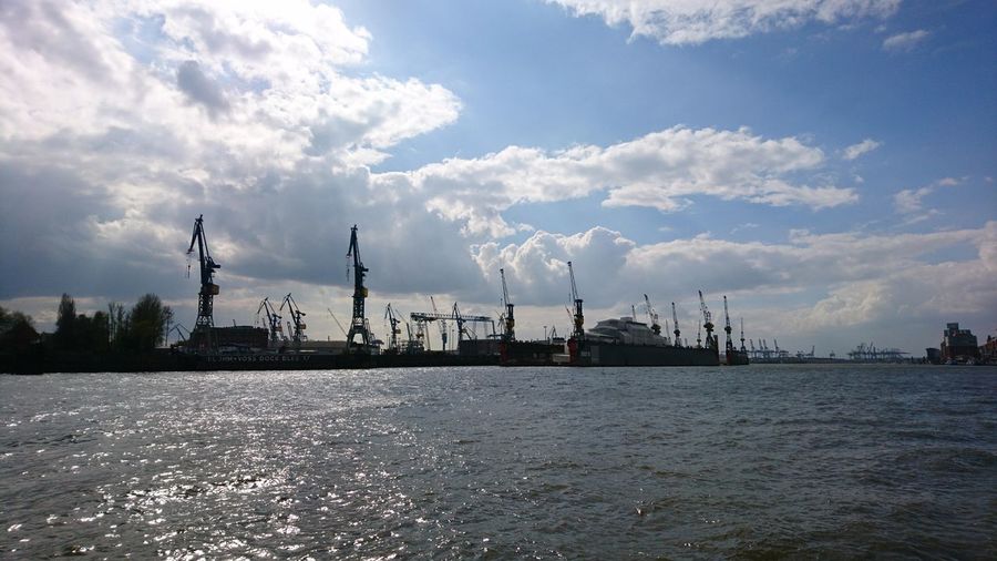 Panoramic view of factory by sea against sky