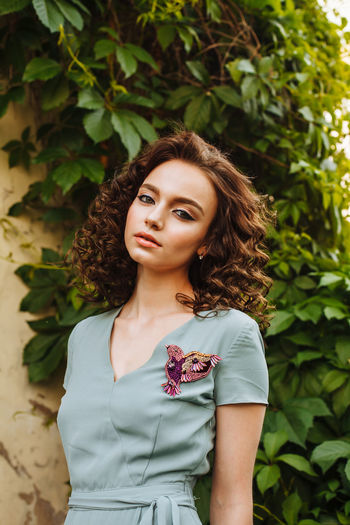 Portrait of young woman wearing make-up while standing against plants