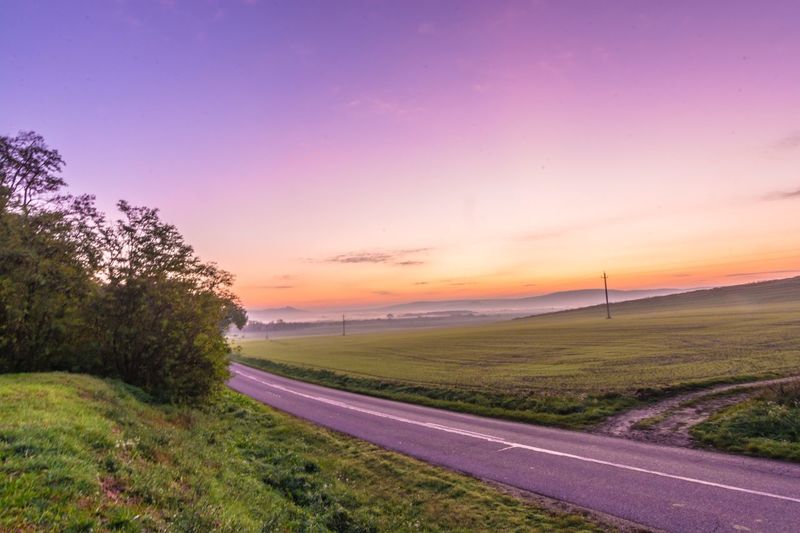 High angle view of road amidst field against sky during sunrise