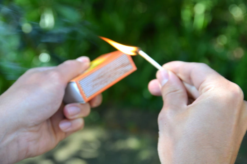 Cropped image of person hands igniting matchstick