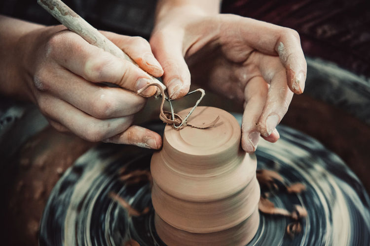Master removes the top layer of clay on pot with a special tool. create clay vessel. 