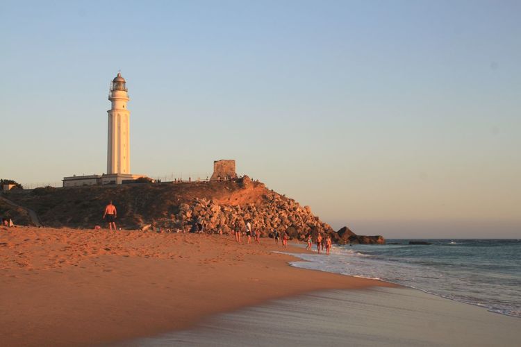 Lighthouse on beach against clear sky