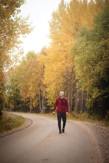 Man aged 23 wearing a checked red and black shirt walks along a foamy path. kainuu region, finland.