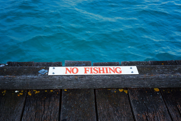 High angle view of no fishing sign on pier by sea