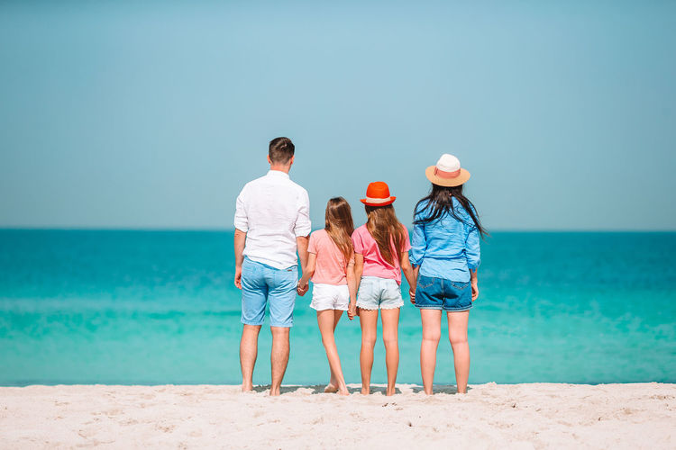 Rear view of family standing on beach