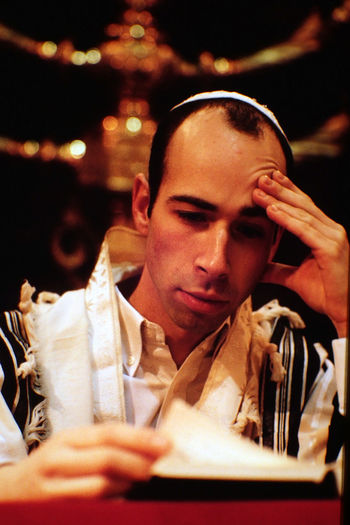 Rabbi reading book against menorah at synagogue