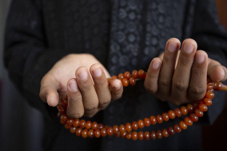 Midsection of woman holding prayer beads