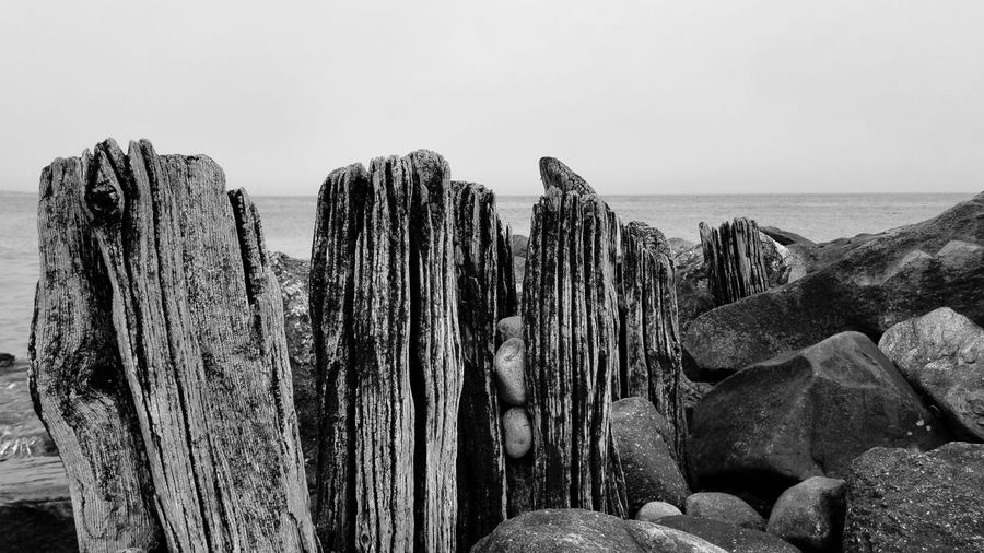 Panoramic view of wooden posts on beach against sky