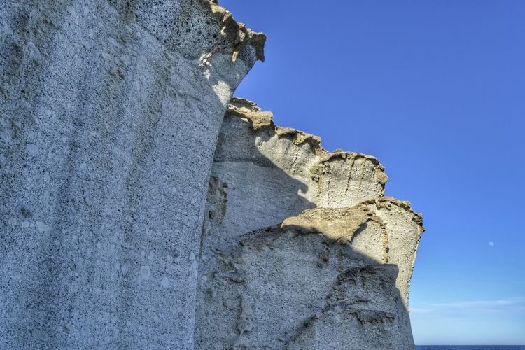 Low angle view of rock against clear blue sky