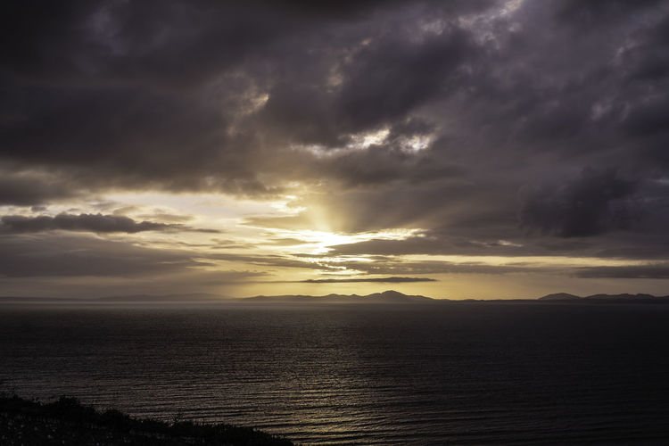 Scenic view of sea against dramatic sky during sunset