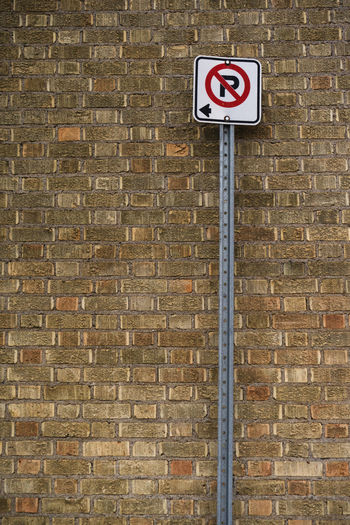 No parking sign against brick wall.