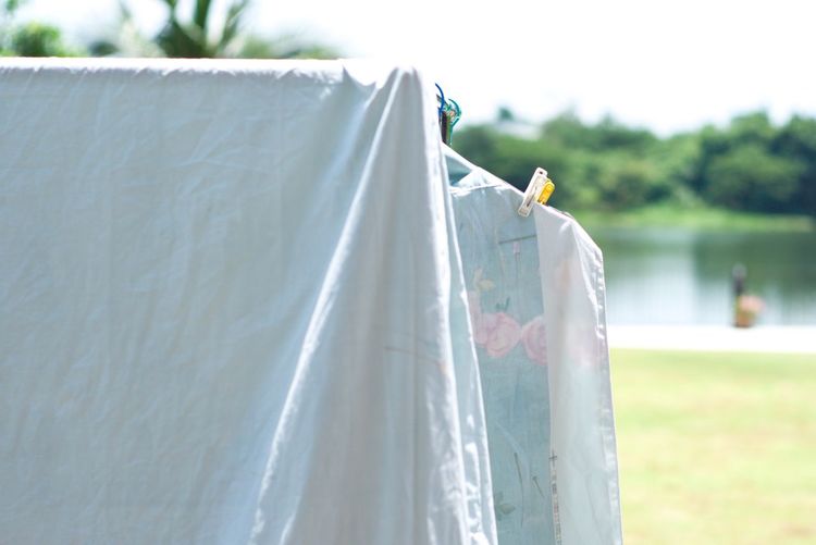 Clothes and flat sheet hanging on the clothesline with clothespin for drying from the heat of sun