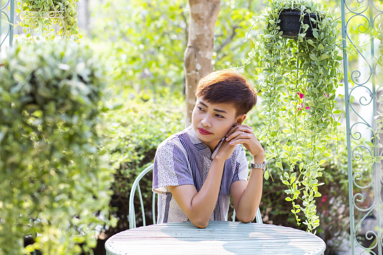 Young woman looking away while sitting on table