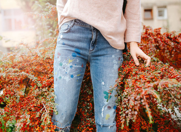 Close up of woman in painted jeans standing in red bush