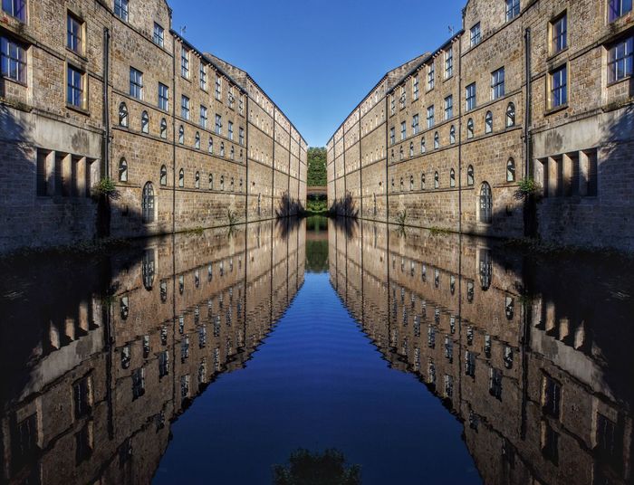 Reflection of buildings in water against clear sky